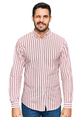Young hispanic man wearing business shirt winking looking at the camera with sexy expression,...