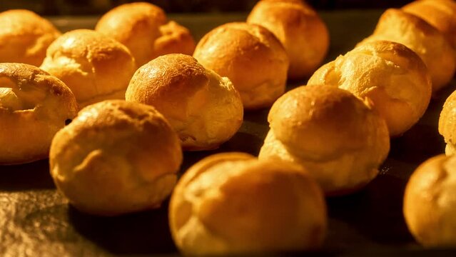 Profiteroles baking in oven. Timelapse of profiterole production. Homemade food growth in oven. Bakery concept. Brewing cake. Close-up in 4K, UHD