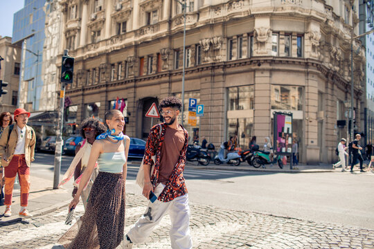 Diverse group of young friends crossing sidewalk downtown