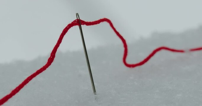 Red thread and needle in snow