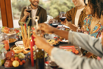 Close up of happy friends enjoying in conversation and drinking wine during festive dinner at home
