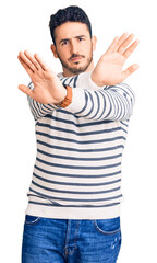 Young hispanic man wearing casual clothes rejection expression crossing arms and palms doing negative sign, angry face
