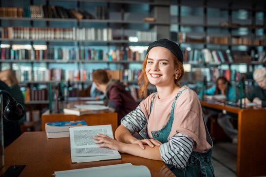 Smiling portrait of young female student reading in library