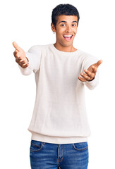 Young african amercian man wearing casual clothes smiling cheerful offering hands giving assistance and acceptance.