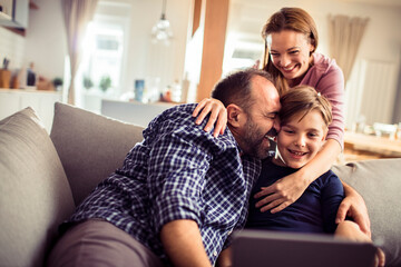 Happy family with child using tablet on couch at home