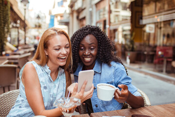 Two young women taking selfie in street cafe - Powered by Adobe