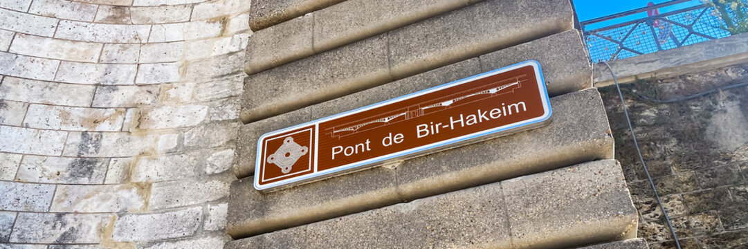 Pont de Bir-Hakeim bridge sign on the stone wall of the bridge on a summer day in Paris, France