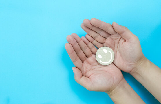 Happy smiling face in the hands, mental health concept, positive thinking, support and evaluation