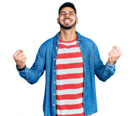 Young hispanic man with beard wearing casual denim jacket very happy and excited doing winner gesture with arms raised, smiling and screaming for success. celebration concept.