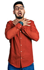 Young hispanic man with beard wearing business shirt and glasses shouting and suffocate because painful strangle. health problem. asphyxiate and suicide concept.