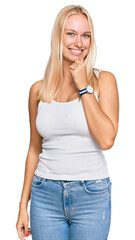 Fototapeta premium Young blonde girl wearing casual style with sleeveless shirt looking confident at the camera smiling with crossed arms and hand raised on chin. thinking positive.