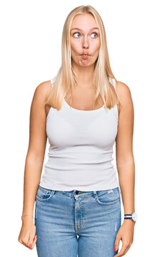 Young blonde girl wearing casual style with sleeveless shirt making fish face with lips, crazy and comical gesture. funny expression.