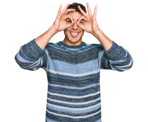 Hispanic young man wearing casual clothes doing ok gesture like binoculars sticking tongue out, eyes looking through fingers. crazy expression.