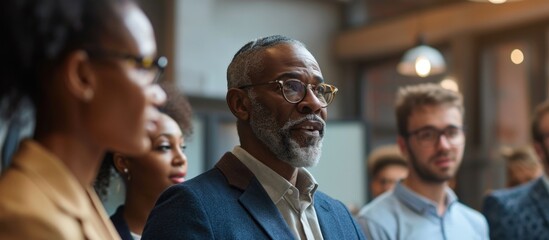 Diverse team of business professionals listen to CEO discuss design, data analysis, and marketing strategy in office conference.