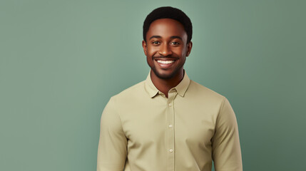 Obraz premium A man in a pastel yellow shirt exudes a calm demeanor with a gentle smile, set against a soft green backdrop that highlights his