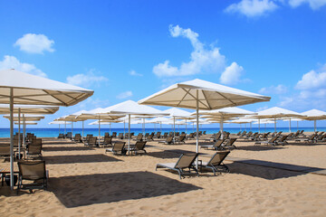 Tropical scenery. Sun beds, loungers, umbrella. Sea. Resort hotel. Rows of folded beach umbrellas...