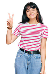 Young hispanic girl wearing casual clothes smiling looking to the camera showing fingers doing victory sign. number two.