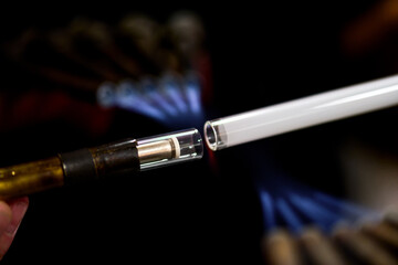 Naklejka premium neon glass blower using fire to melt electrode to neon glass tube