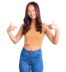 Young beautiful chinese girl wearing casual clothes looking confident with smile on face, pointing...