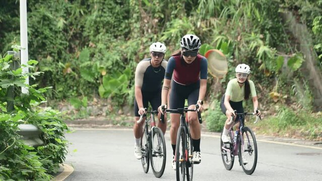 young asian cyclists training on slope of rural road