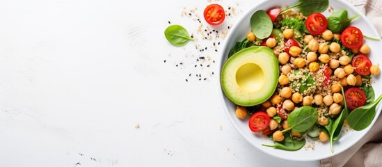 Top view vegetable salad with quinoa, avocado, tomato, spinach, and chickpeas - on white table. - obrazy, fototapety, plakaty