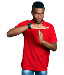 Young african american man wearing casual red t shirt doing time out gesture with hands, frustrated and serious face
