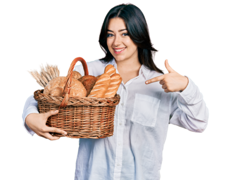 Beautiful hispanic woman holding wicker basket with bread smiling happy pointing with hand and finger