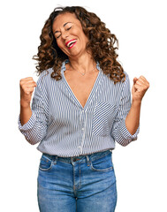 Middle age hispanic woman wearing casual clothes very happy and excited doing winner gesture with arms raised, smiling and screaming for success. celebration concept.