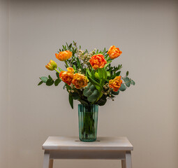 A bouquet of peach and orange colored roses on a small table.