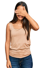 Fototapeta premium Beautiful hispanic woman wearing casual clothes smiling and laughing with hand on face covering eyes for surprise. blind concept.