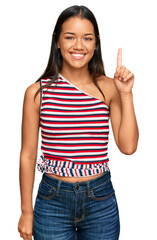 Beautiful hispanic woman wearing casual clothes showing and pointing up with finger number one while smiling confident and happy.