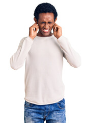 Fototapeta premium African handsome man wearing casual winter sweater covering ears with fingers with annoyed expression for the noise of loud music. deaf concept.