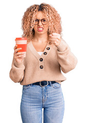 Young blonde woman with curly hair wearing glasses and drinking a cup of coffee annoyed and frustrated shouting with anger, yelling crazy with anger and hand raised