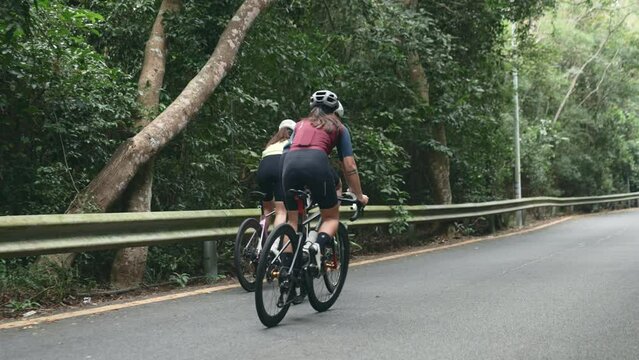 rear view of three asian cyclists training on a uphill country road