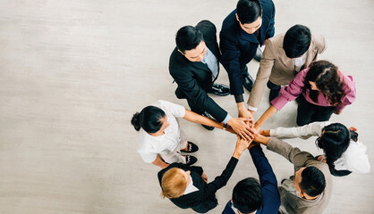 Top view of four diverse colleagues in a circle hands stacked as they symbolize unity and teamwork. This image conveys the values of success and global cooperation in business.
