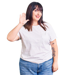 Obraz premium Young plus size woman wearing casual clothes waiving saying hello happy and smiling, friendly welcome gesture