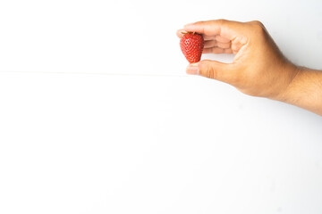  man's hand holding fresh organic strawberries on a neutral white background