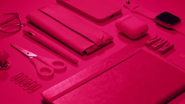 Office school stuff equipment on pink background close-up. Composition of books, pens, glasses, headphones, watches in pink color 