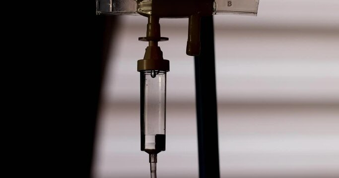 This evocative stock footage offers a slow motion silhouette of an IV drip, an emblem of life saving treatment, set against the soft, fluctuating lights of an ambulance. The clip artfully captures the