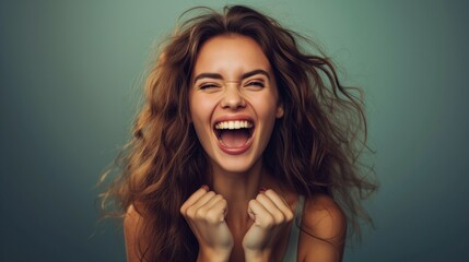 Euphoric young woman with flowing hair celebrates with a triumphant shout, exuding happiness and success against a teal backdrop - obrazy, fototapety, plakaty