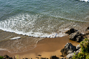 Playa soleada con olas rompiendo.
