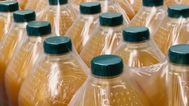 Rows of five-liter plastic bottles of orange juice stand in the warehouse of a wholesale store