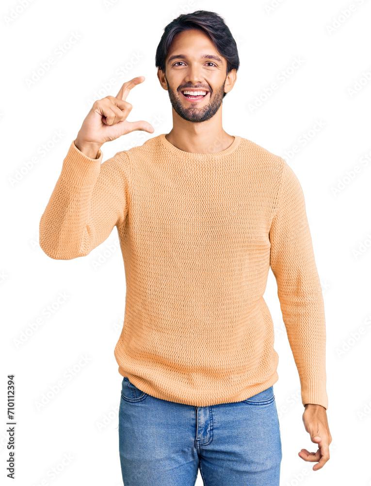 Canvas Prints Handsome hispanic man wearing casual sweater smiling and confident gesturing with hand doing small size sign with fingers looking and the camera. measure concept.