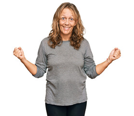 Obraz premium Middle age blonde woman wearing casual clothes very happy and excited doing winner gesture with arms raised, smiling and screaming for success. celebration concept.