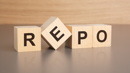 four wooden cubes with the letters REPO on the bright surface of a brown table, business concept