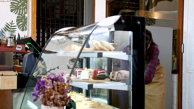 Asian barista waitress worker female selling bakery in cafe coffee shop restaurant, small business entrepreneur start-up happy service customer indoor, businesswoman multitask owner working lifestyle
