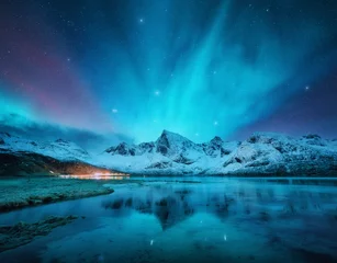 Poster Northern lights over the snowy mountains, frozen sea, reflection in water at winter night in Lofoten, Norway. Aurora borealis and snowy rocks. Landscape with polar lights, starry sky and fjord. Nature © den-belitsky