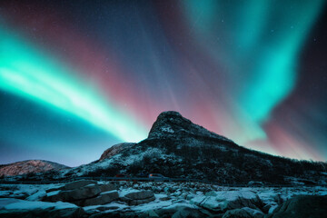 Northern lights and snowy mountains at night in Lofoten, Norway. Aurora borealis above the snow...
