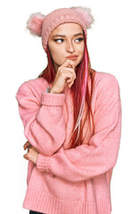 Young caucasian woman wearing casual clothes and wool cap with hand on chin thinking about question, pensive expression. smiling with thoughtful face. doubt concept.