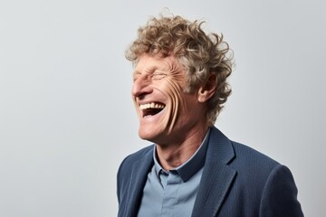 Portrait of a happy senior man laughing against a grey background.